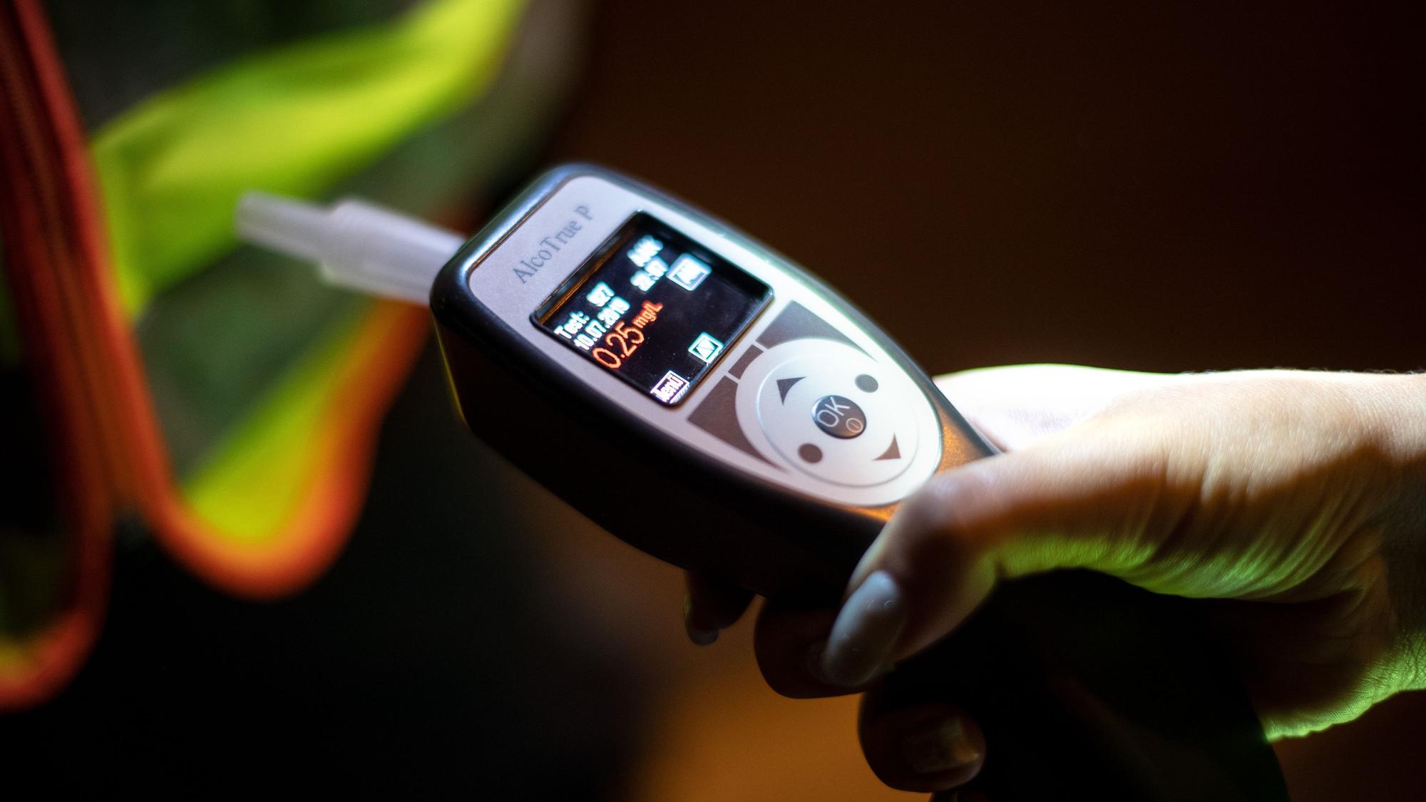 Eine FPolizistin hält ein Gerät in der Hand, mit dem Atemalkoholtests durchgeführt werden.