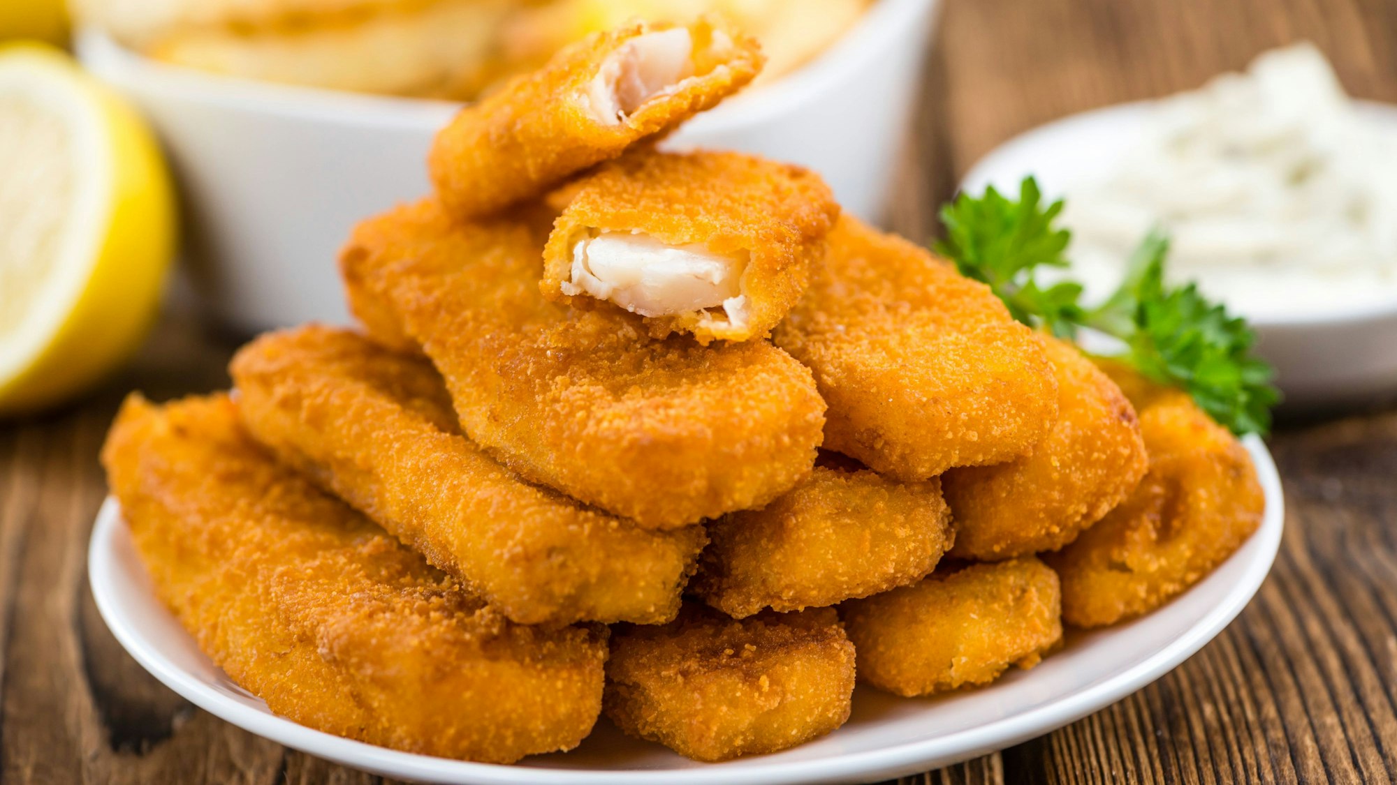 Fischstäbchen liegen angerichtet auf einem Teller.