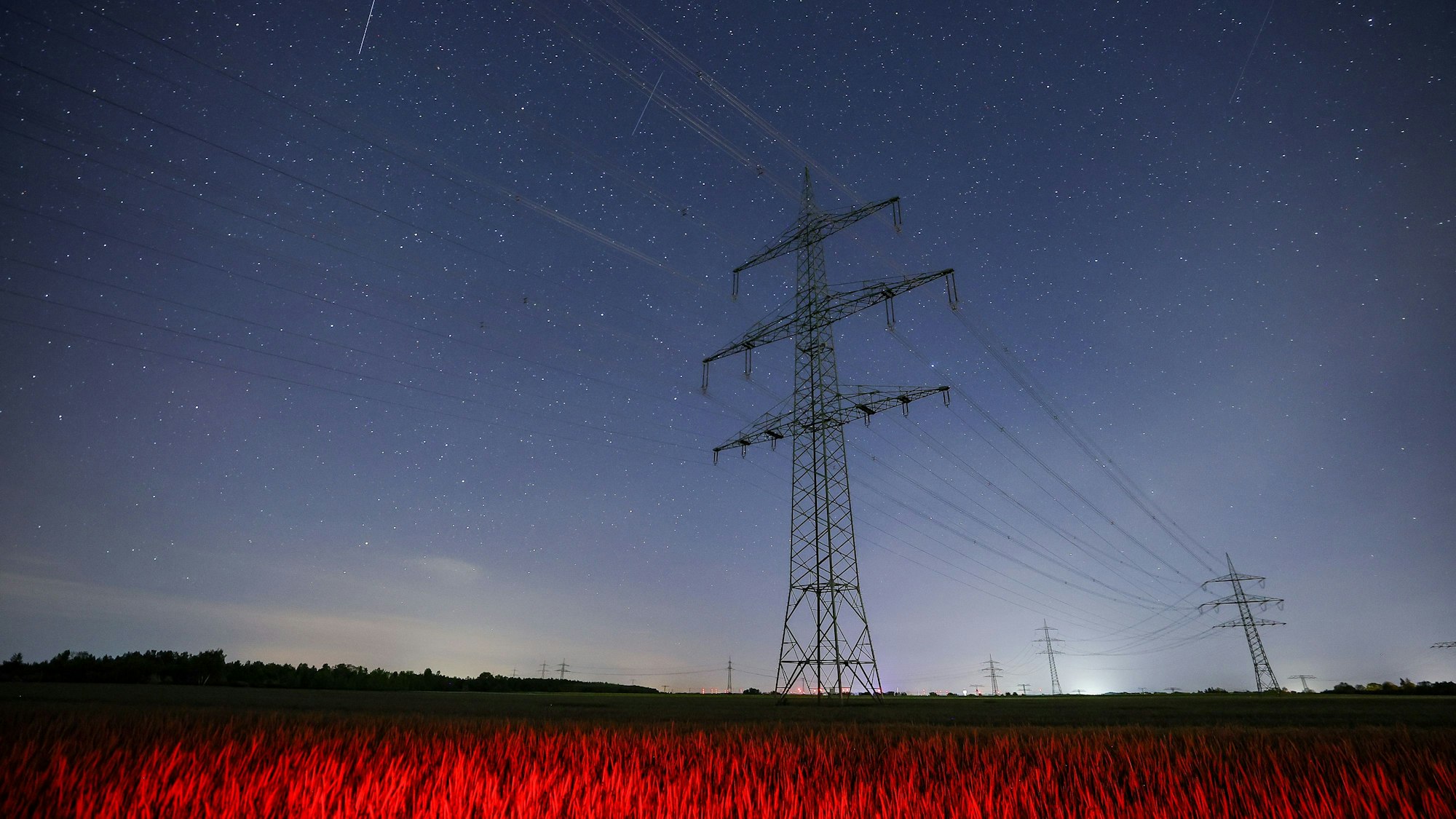 Der Sternenhimmel ist hinter einer Hochspannungsleitung zu sehen.
