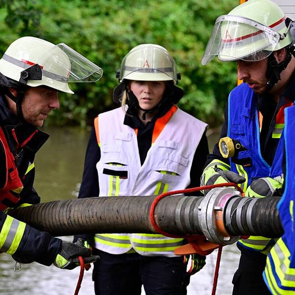 Feuerwehrleutemontieren einen Saugschlauch, um Löschwasser aus einem Fluss im Hintergrund zu fördern.