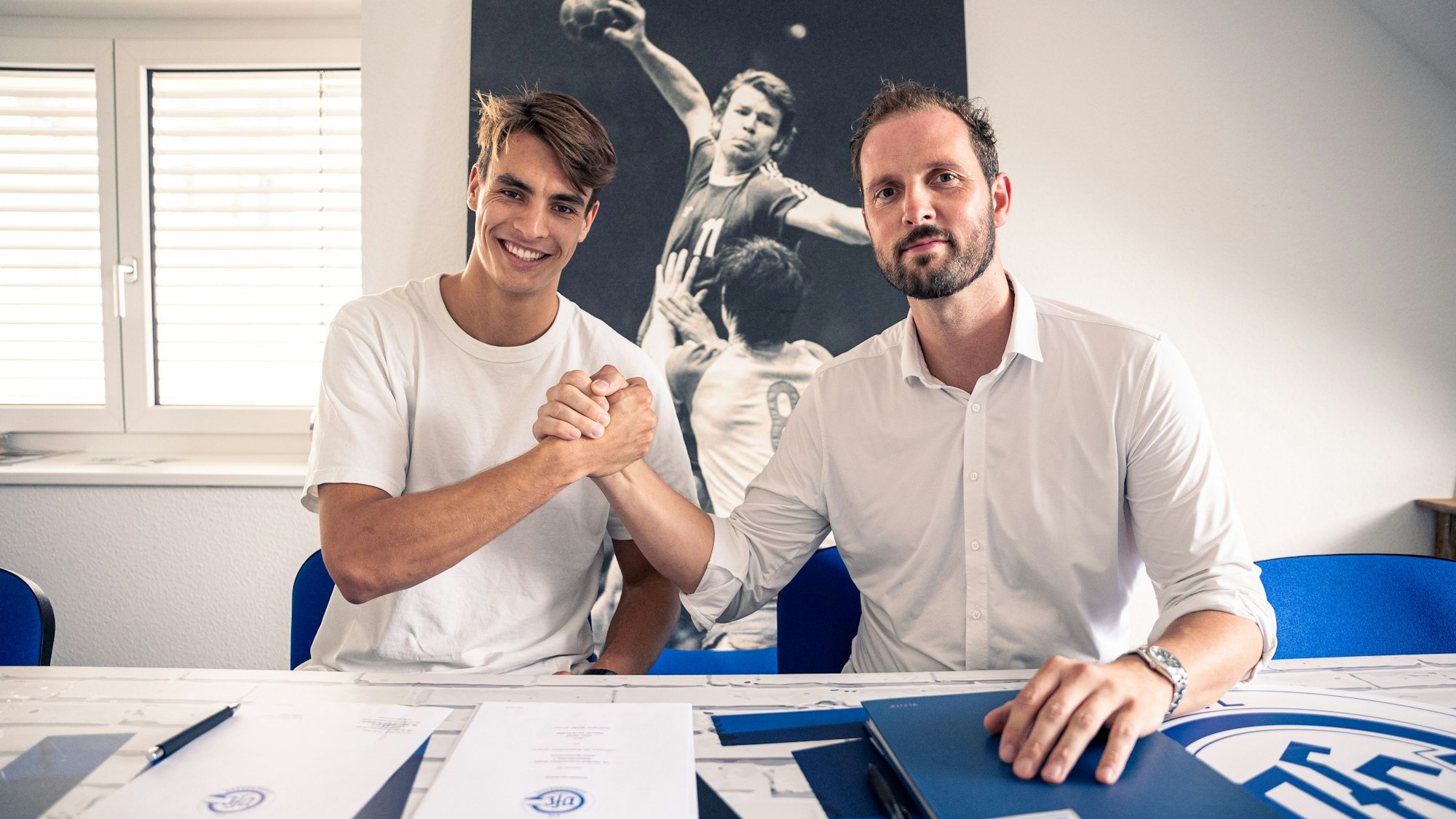 Handballer Julian Köster und VfL-Geschäftsführer Christoph Schindler sitzen nebeneinander und schlagen mit den Händen ein.