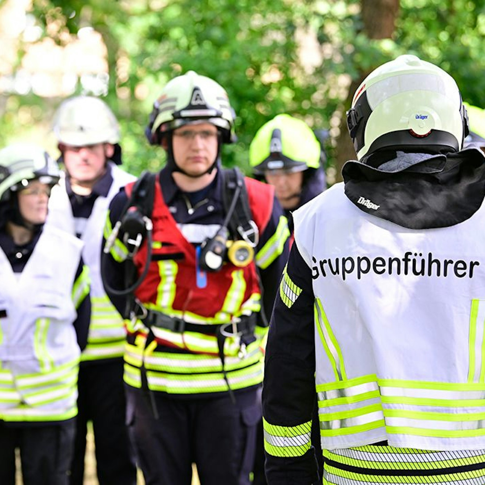 Eine Gruppe von Feuerwehrleuten ist angetreten, vor ihr steht ein Feuerwehrmann mit einer Weste auf der „Gruppenführer“ zu lesen ist.