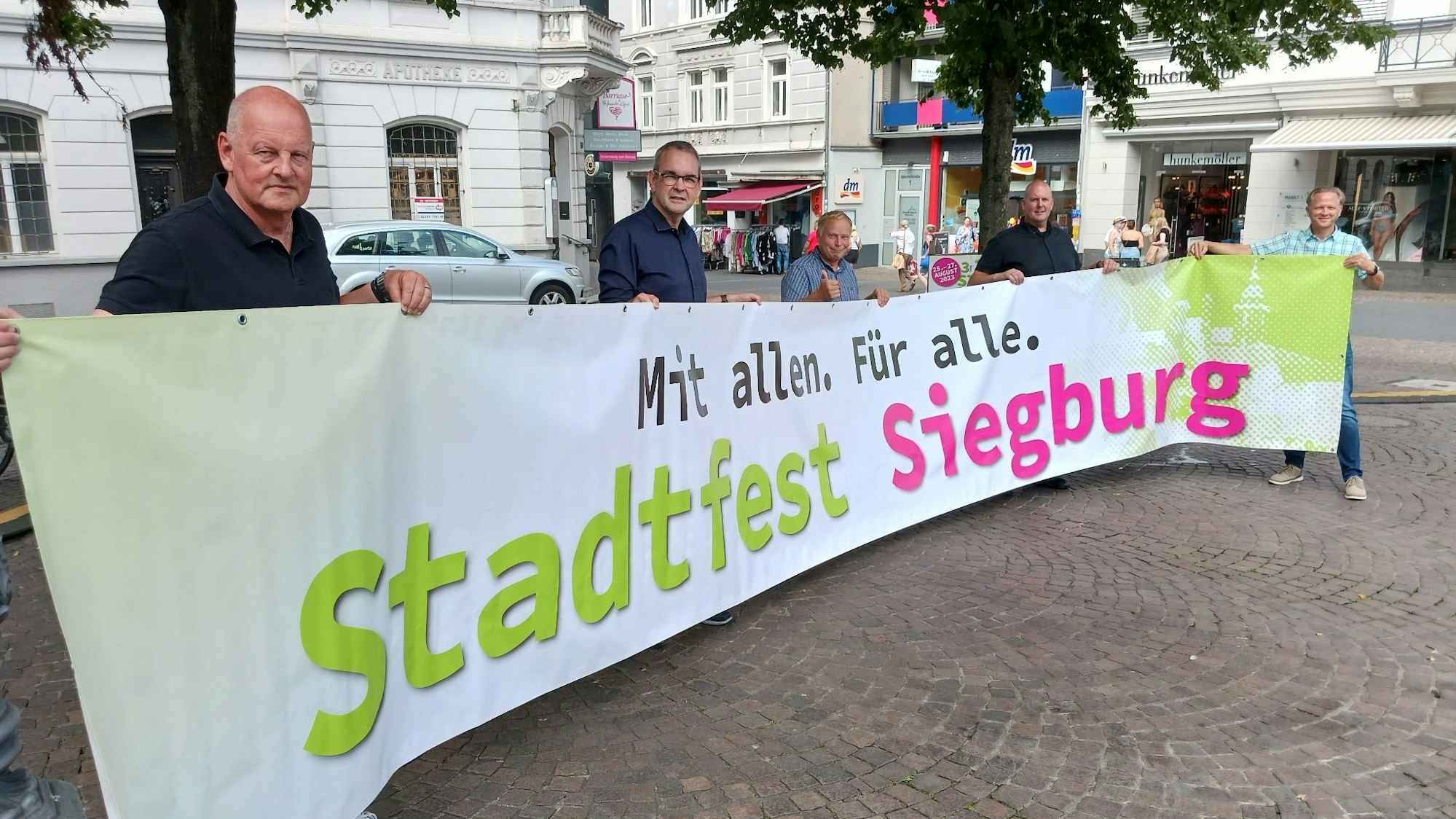 Fünf Männer halten ein Transparent mit einer Werbung für das Siegburger Stadtfest