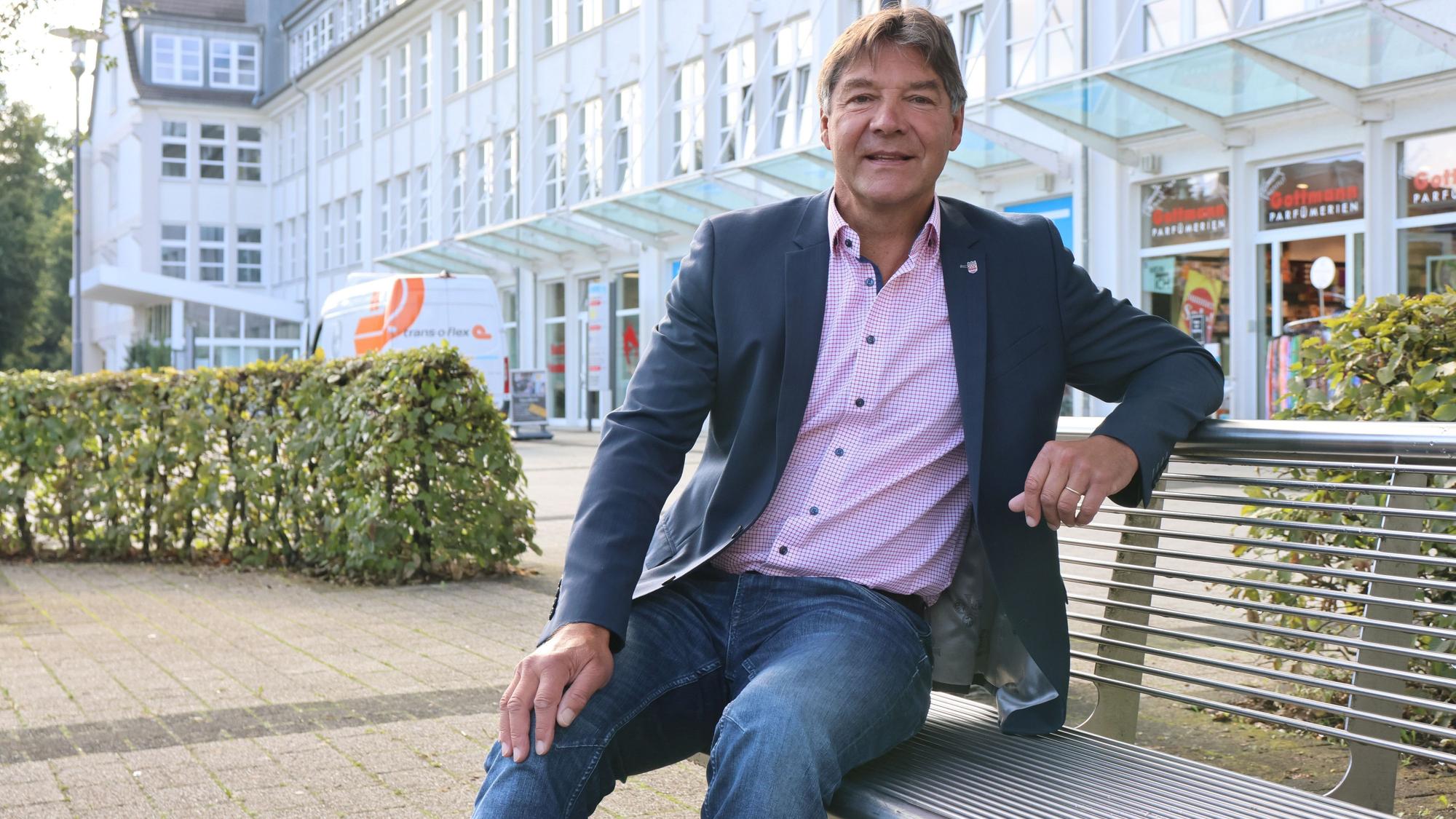 Zu sehen ist ein Mann, der vor dem Rathaus in Bergneustadt auf einer Bank sitzt.