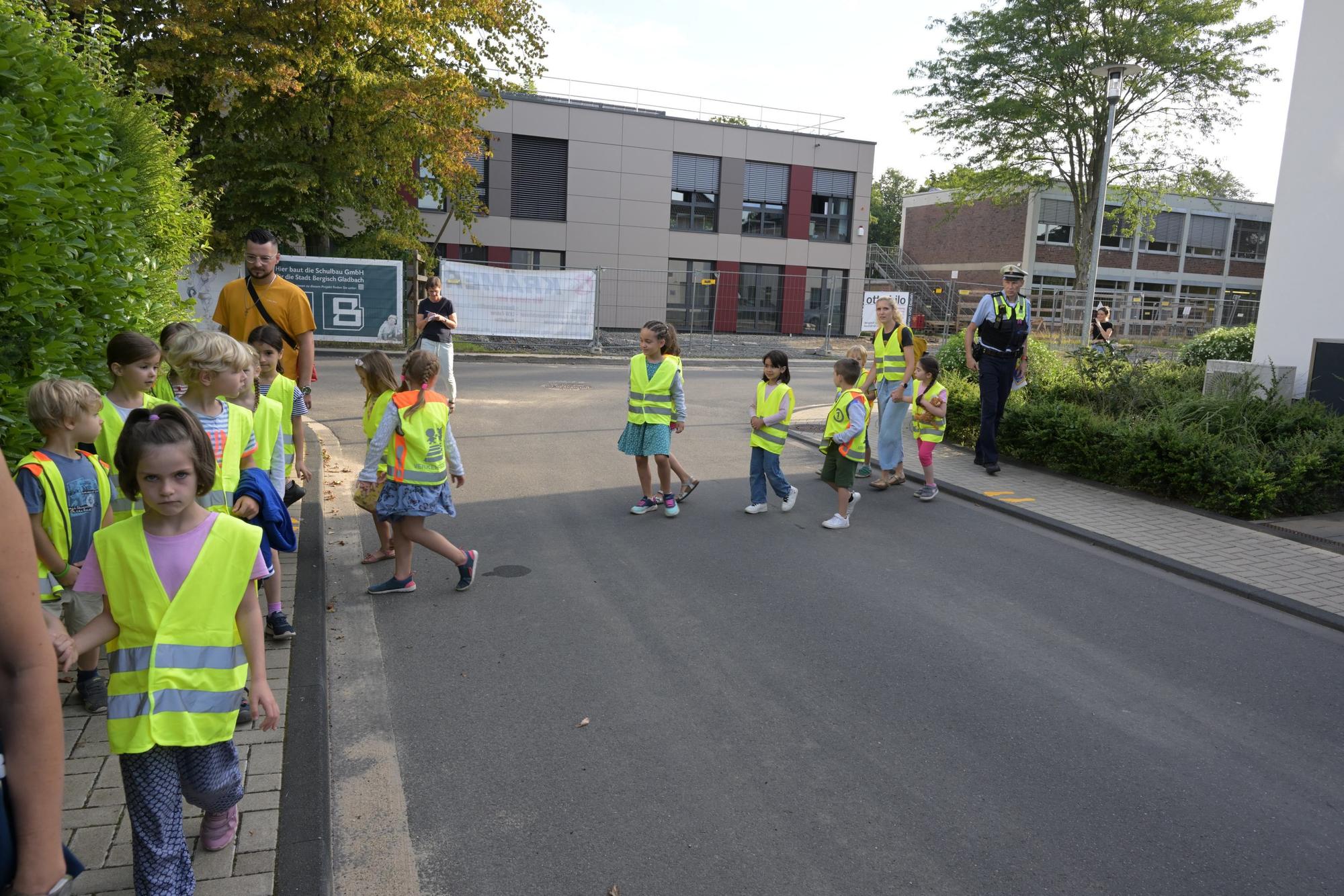 Kinder gehen hintereinander. Geführt werden sie von zwei Eltern.