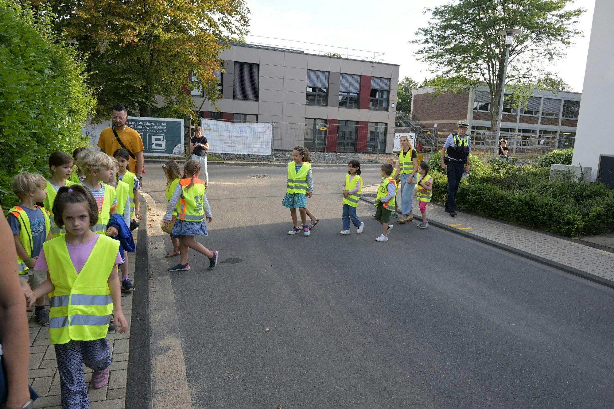 Kinder gehen hintereinander. Geführt werden sie von zwei Eltern.