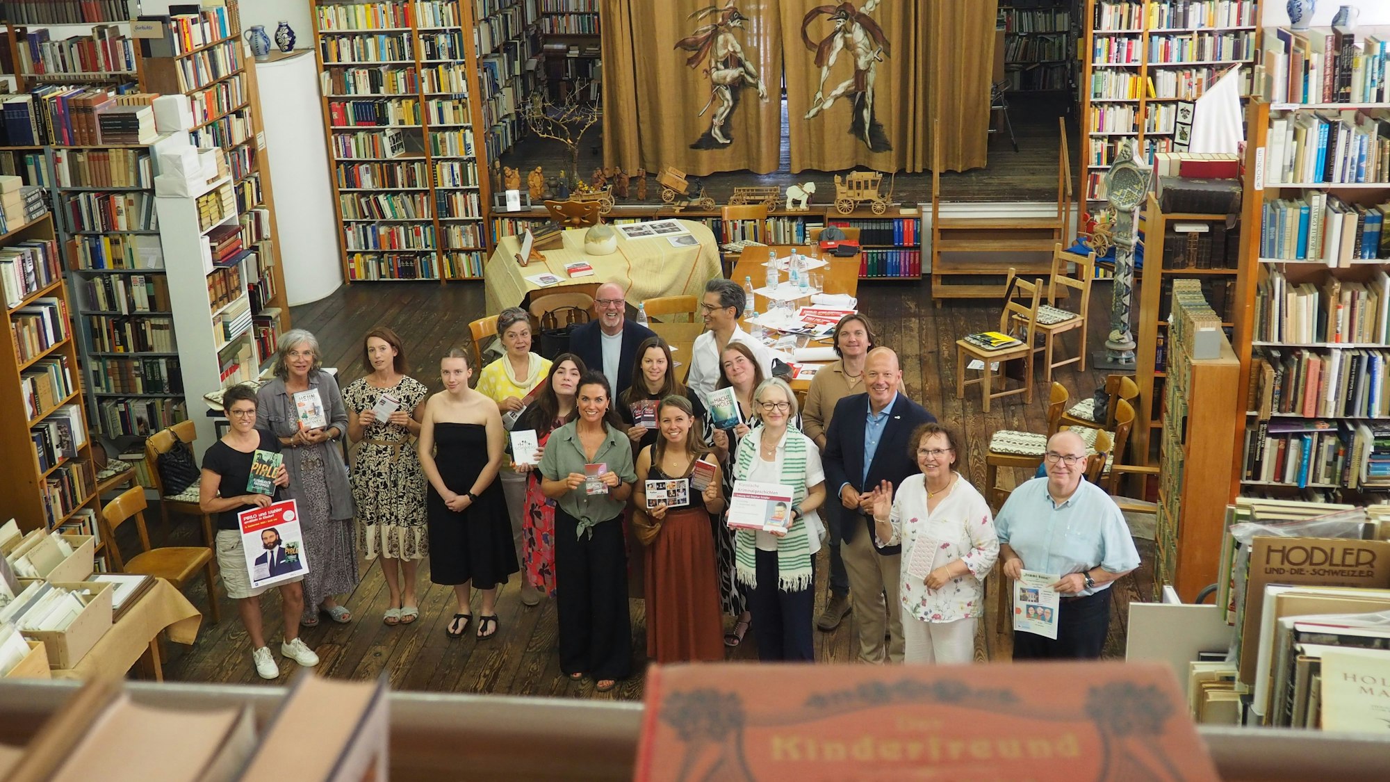 Eine Gruppe Menschen steht zwischen Regalen voller alter Bücher.