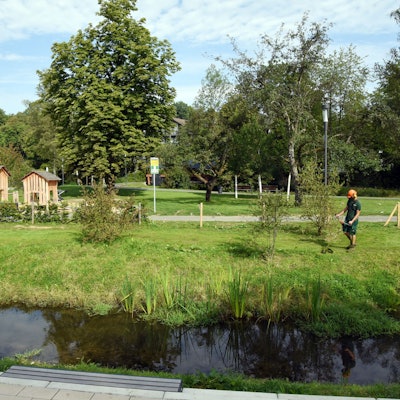 Ein Mann mäht mit einer Elektrosense eine Wiese im Wiehlpark.