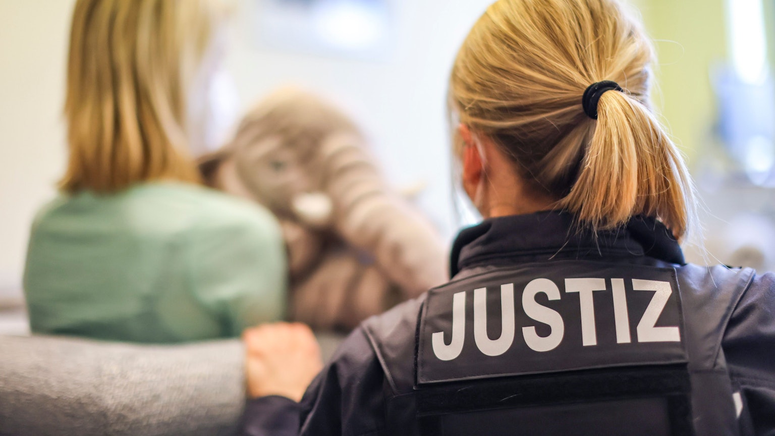 Eine Justizbeamtin und eine junge Frau zeigen exemplarisch eine Zeugenvernehmung.