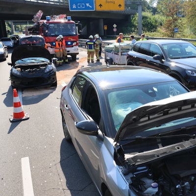 Mehrere beschädigte Autos stehen auf zwei Fahrspuren. Im Hintergrund ist die Feuerwehr zu sehen.
