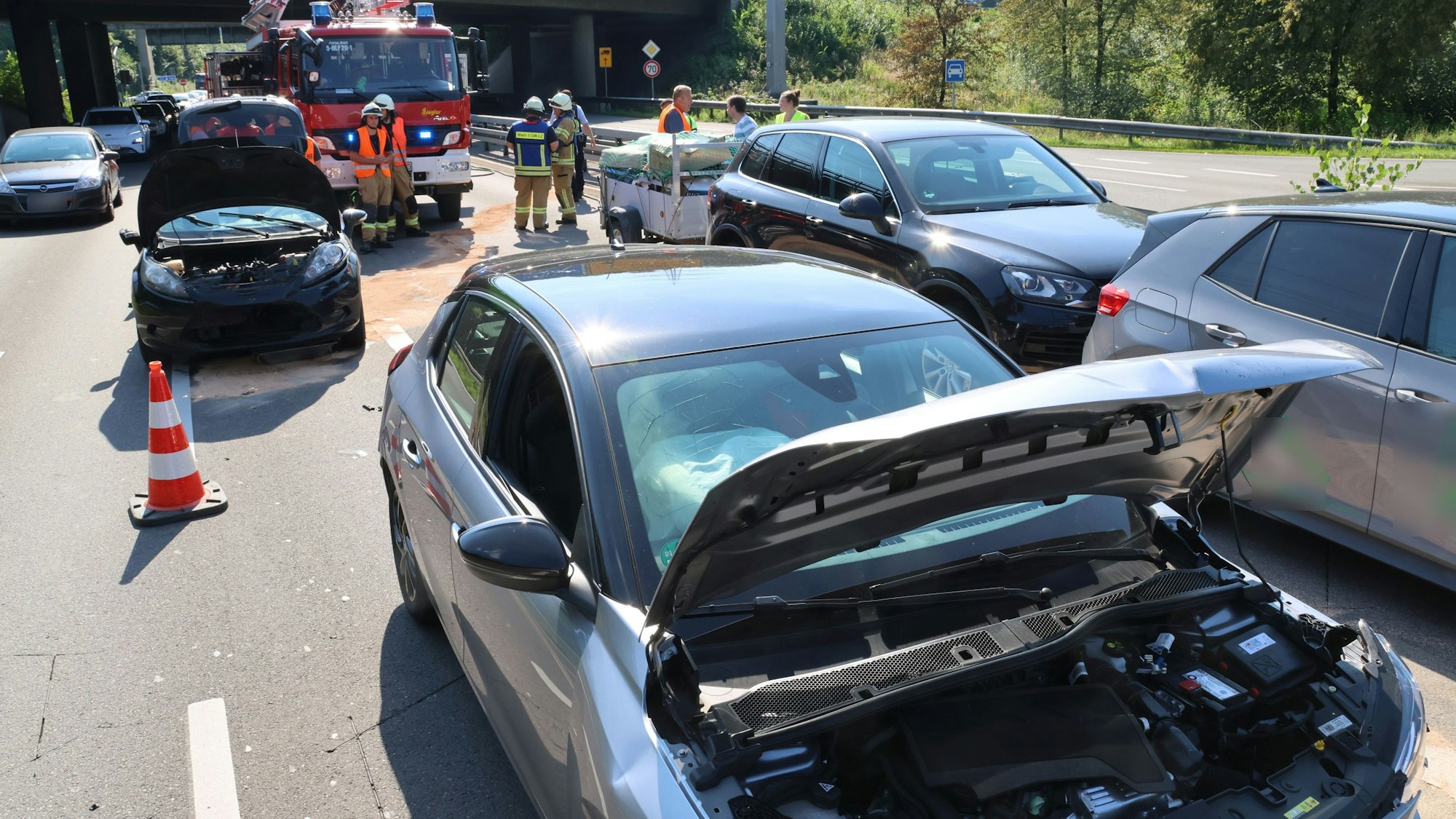 Mehrere beschädigte Autos stehen auf zwei Fahrspuren. Im Hintergrund ist die Feuerwehr zu sehen.