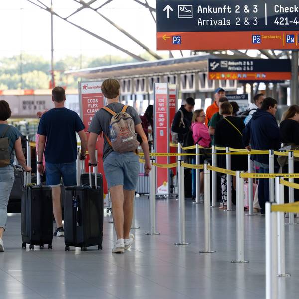 Reisende gehen im Flughafen Köln/Bonn durch die Abflughalle.