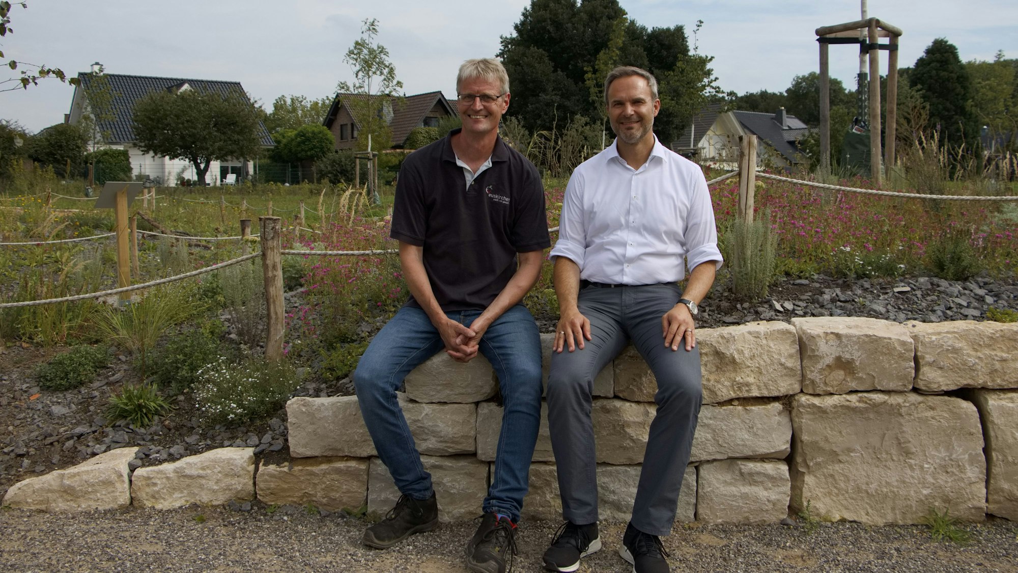 Olaf Spekkers vom Sachgebiet Grünflächen und Forsten und der Technische Beigeordnete der Stadt, Wolfgang Honecker, sitzen auf einem Mäuerchen.