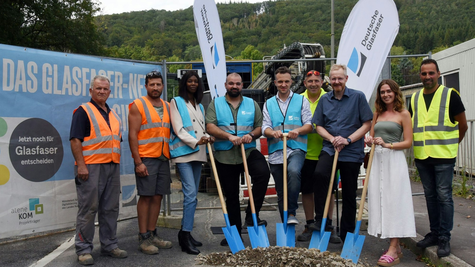 Neun Vertreter von Firmen, der Deutschen Glasfaser und der Stadt Bergneustadt stehen mit Spaten in der Hand auf einer Straße im Gewerbegebiet Pernze.