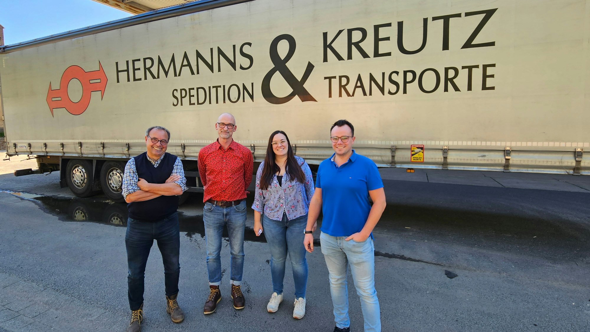Drei Männer und eine Frau, Bernd Kreutz, Thomas Marquardt, Annika und Axel Kreutz, stehen vor einem Lkw-Auflieger von Hermanns und Kreutz.