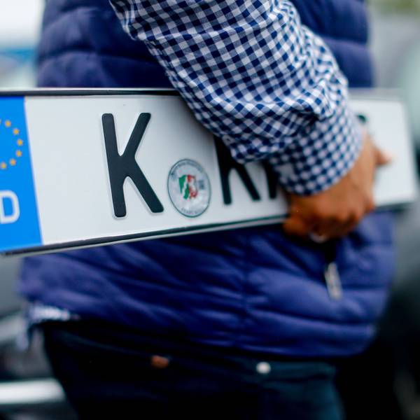 Ein Kunde trägt Nummernschilder vor der Kfz-Zulassungsstelle in Köln-Poll