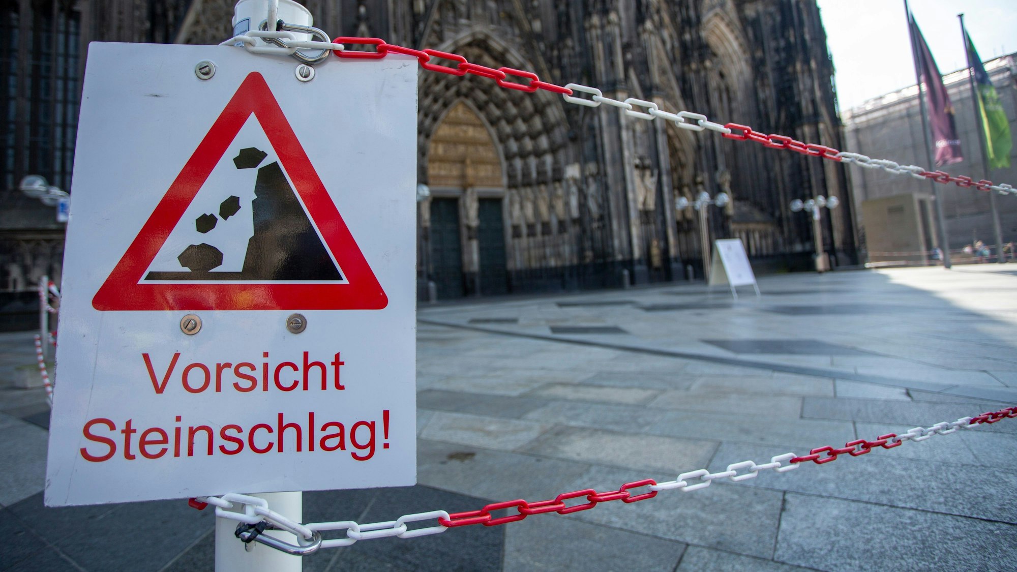 Auf einem Schild auf der Domplatte steht „Vorsicht Steinschlag“