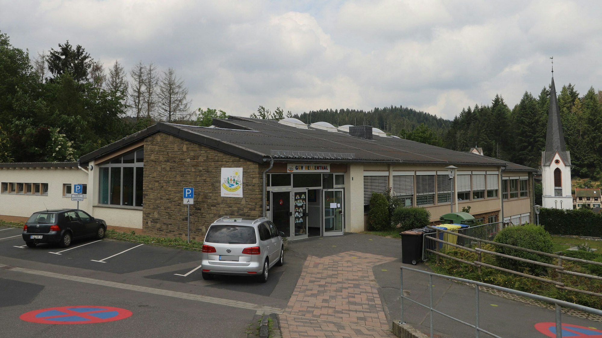 Die Grundschule Hellenthal ist im Vordergrund zu sehen, im Hintergrund ein Kirchturm.