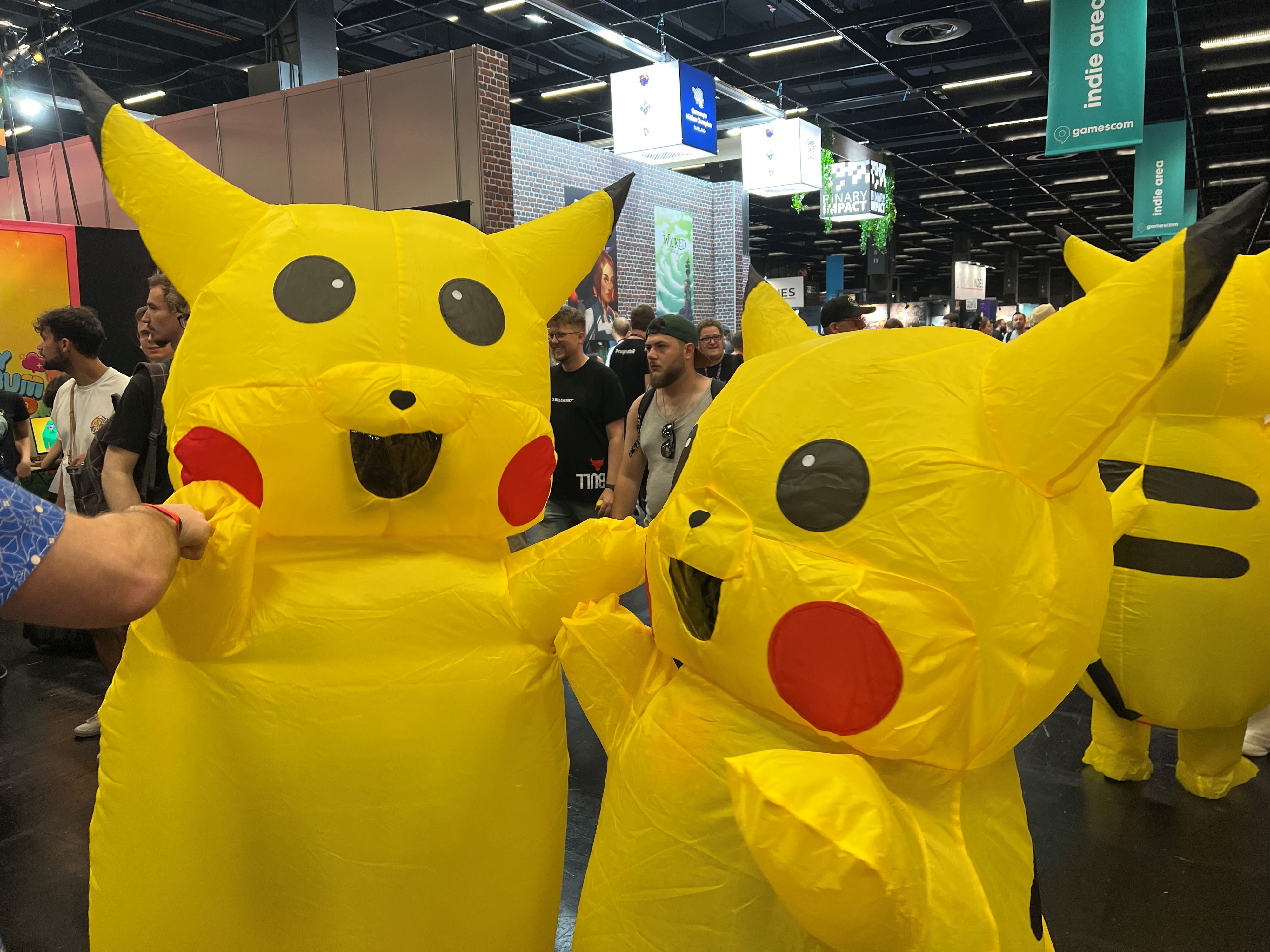 Blick in eine Messehalle, im Vordergrund zwei lebensgroße Figuren Tamagotchis Pikachu.