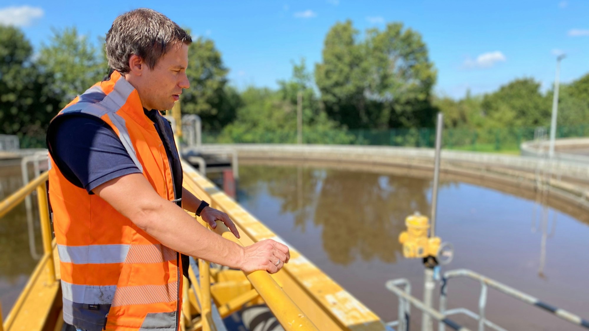 Sebastian Kordel steht auf der Brücke über dem Vorklärbecken in der Kläranlage Weilerswist.