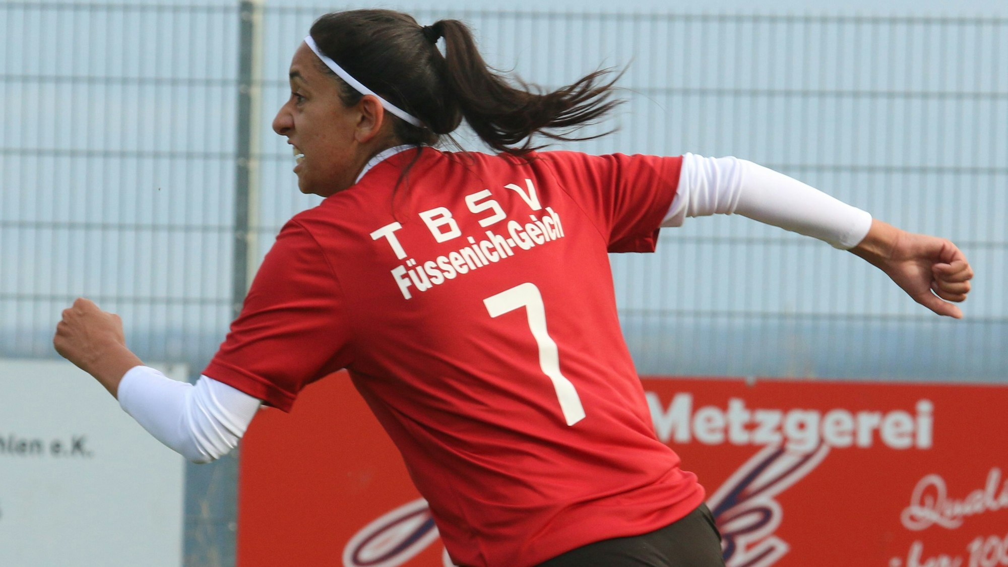 Das Bild zeigt eine Fußballerin, die nach einem Torerfolg jubelnd abdreht.