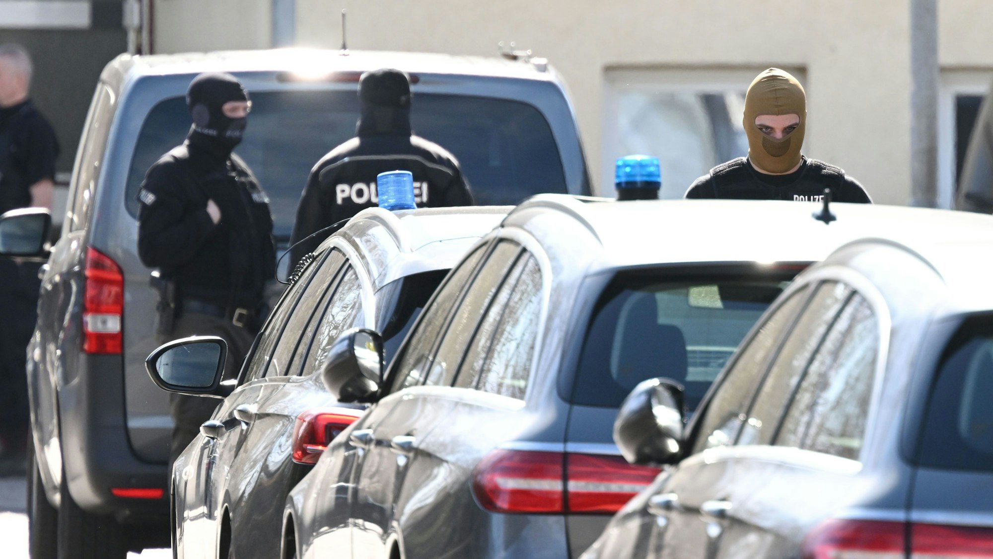 Einsatzkräfte der Polizei stehen nach einer Razzia an Einsatzfahrzeugen (Symbolbild).