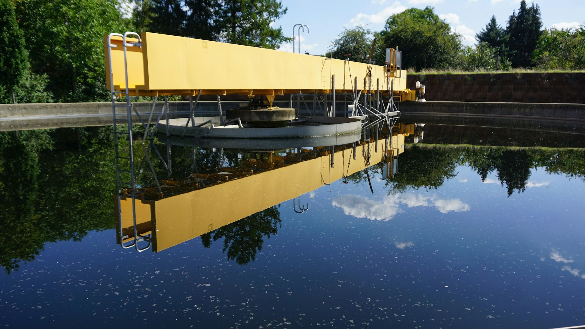 Das Bild zeigt das Nachklärbecken. Im Wasser spiegelt sich der Himmel.