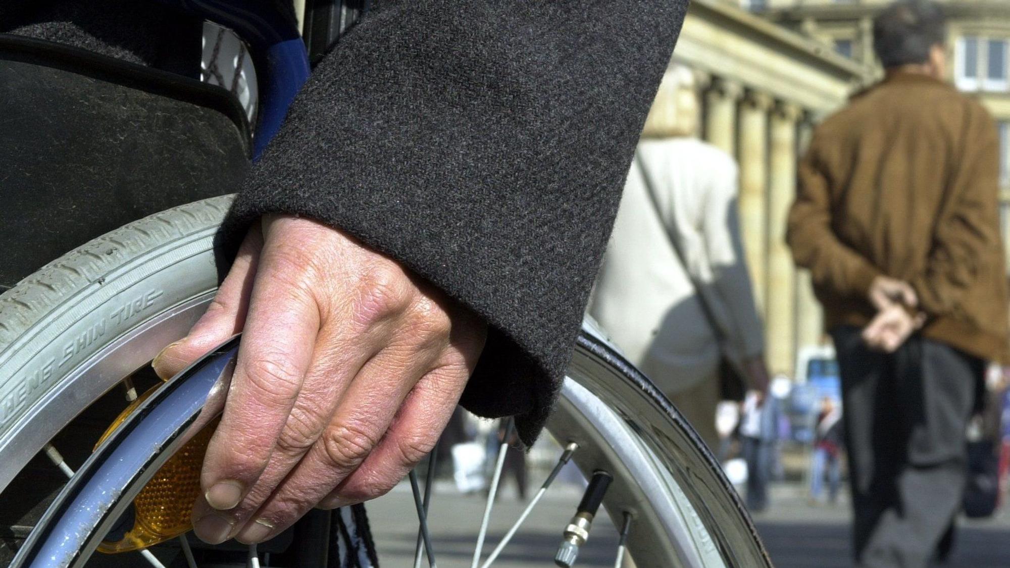Die Hand eines Rollstuhlfahrers liegt auf dem Stuttgarter Schlossplatz auf dem Rad.
