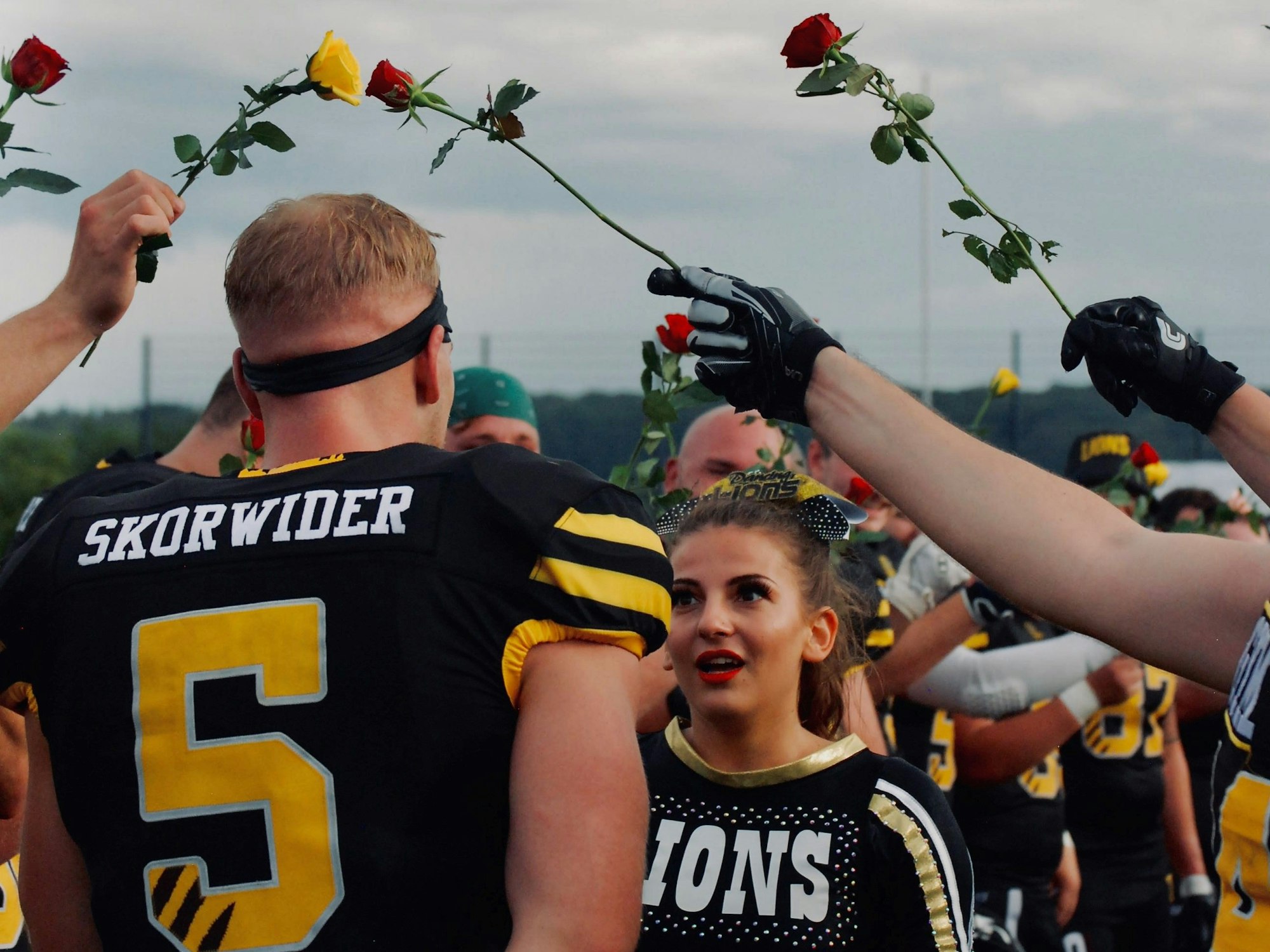 Das Bild zeigt Robin Skorwider und Mariana Asenova, die durch ein Rosenspalier geht.