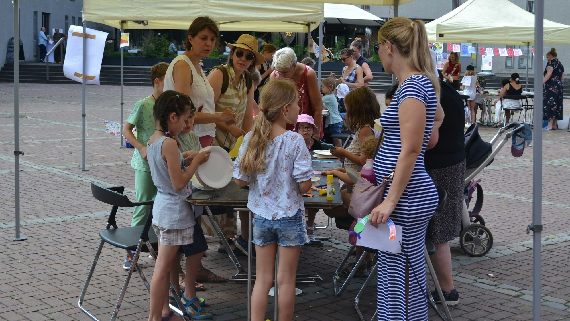 Kinder und Erwachsene drängen sich um einen Tisch mit Zeichenmaterial.
