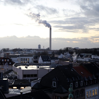 Die Innenstadt von Bergisch Gladbach, im Hintergrund ein qualmender Fabrikschornstein