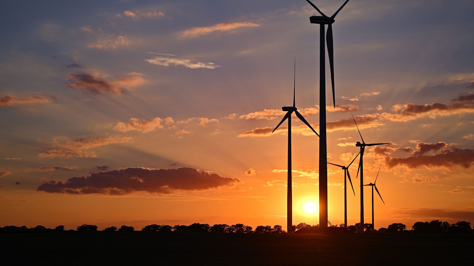 Fünf Windräder in einem Windpark in der Abendsonne.