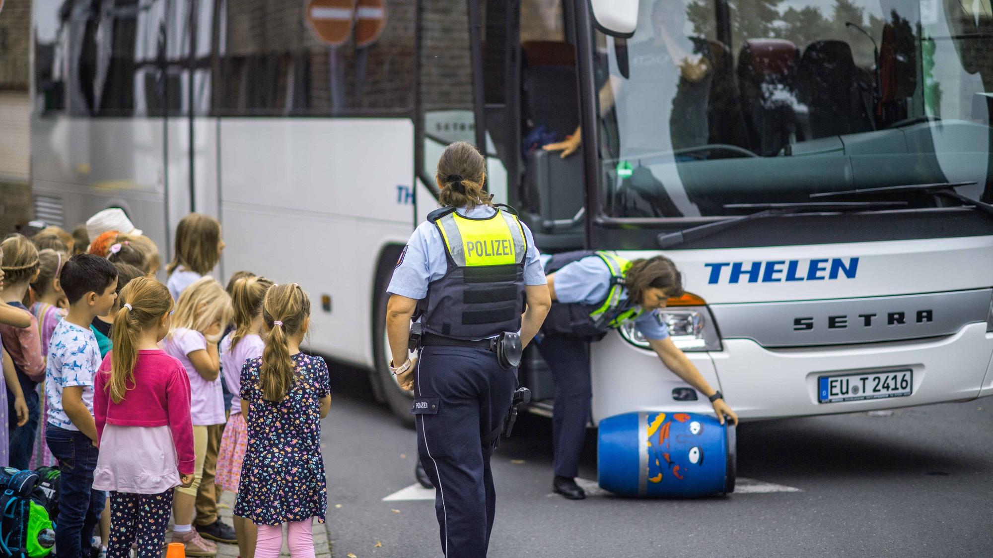 Das Bild zeigt zwei Polizistinnen und eine Gruppe von Grundschülern.
