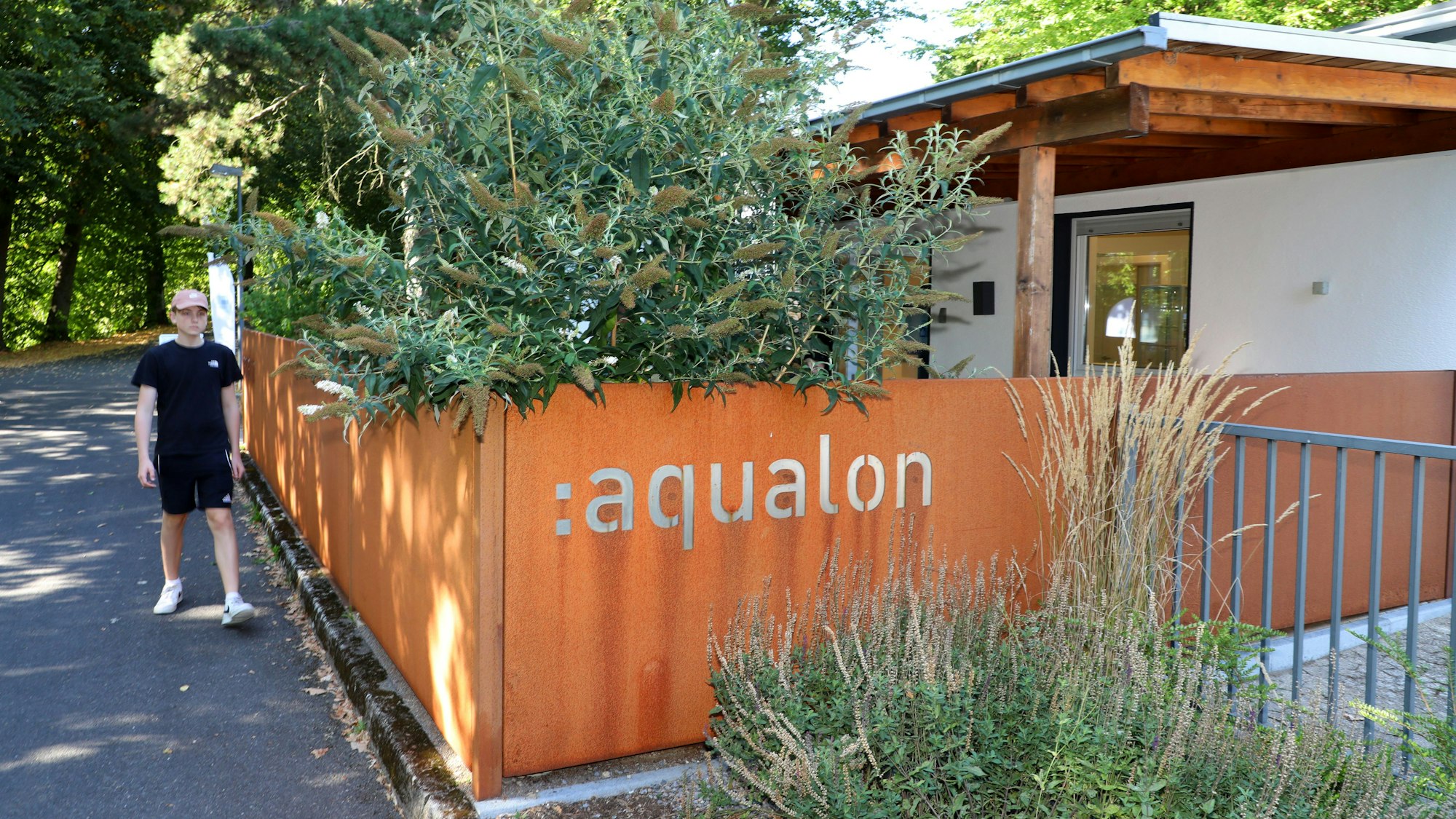 Ein Jugendlicher geht an einem Gebäude vorbei mit der Aufschrift „Aqualon“.