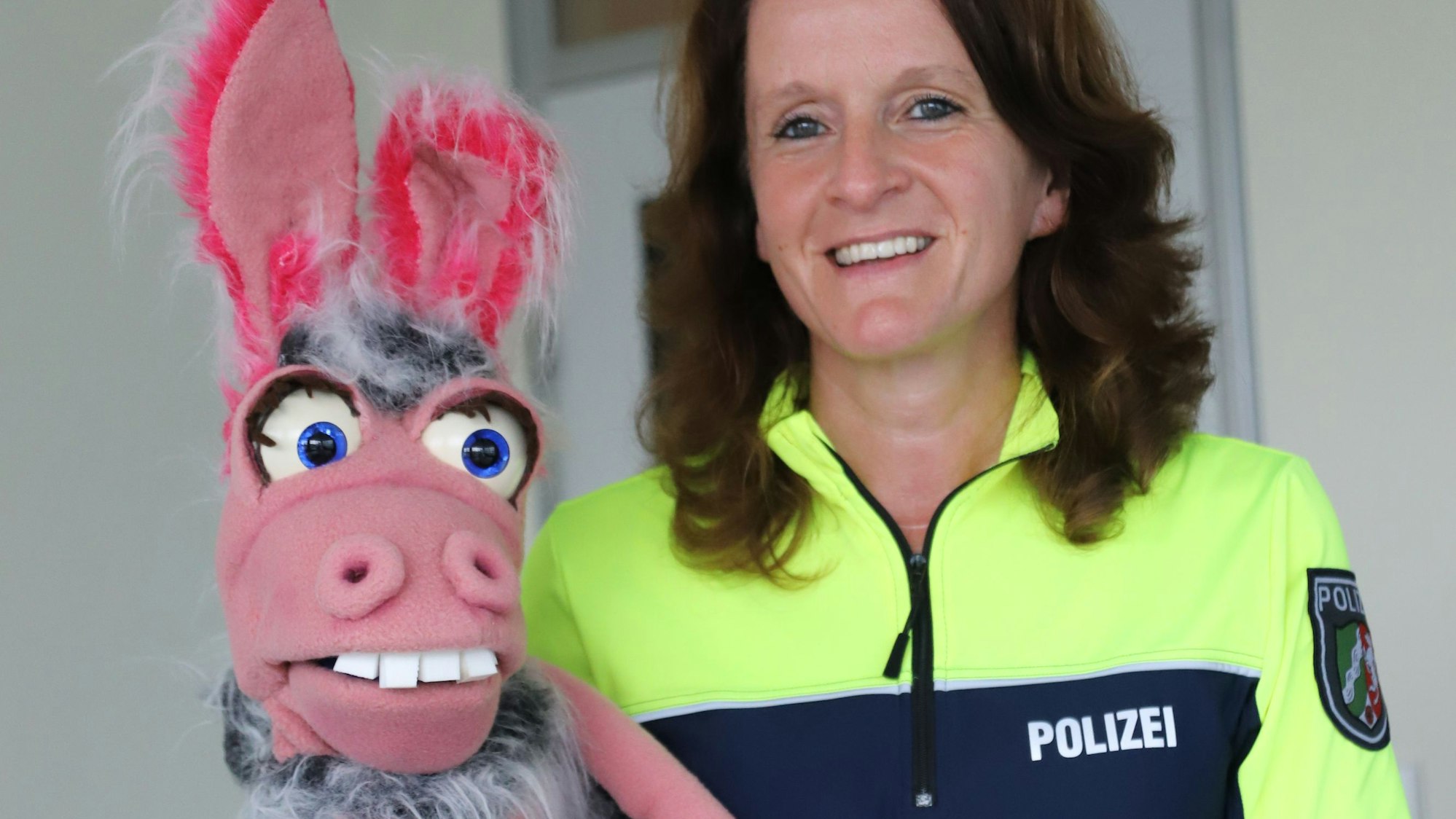 Eine Polizistin hält eine rosa Pferdepuppe.