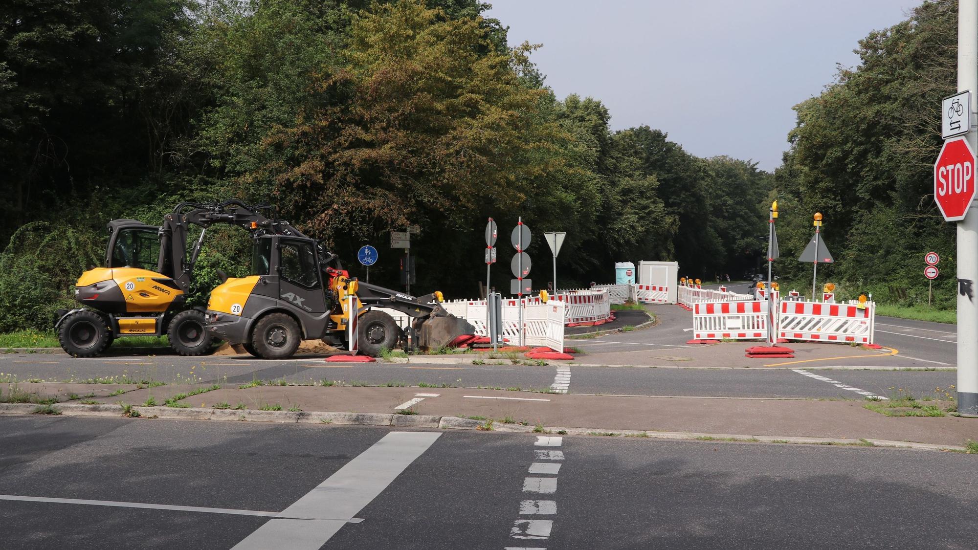 Auf einer Straße stehen Baken und Baumaschinen.