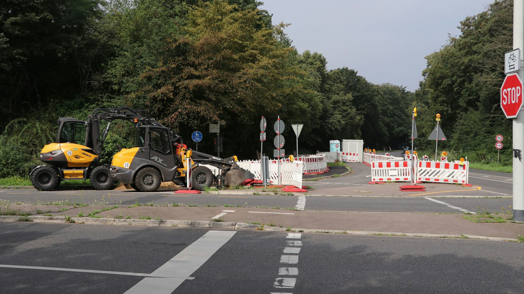 Auf einer Straße stehen Baken und Baumaschinen.