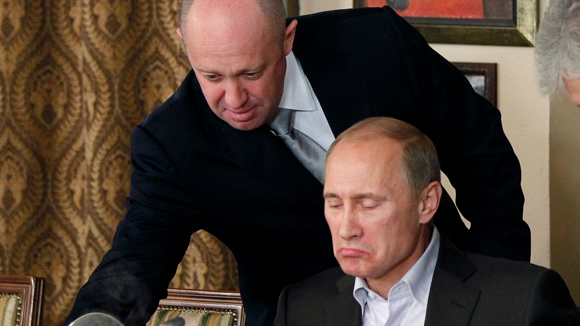 ARCHIV - 11.11.2011, Russland, Moskau: Jewgeni Prigoschin (oben), Chef der Söldnertruppe Wagner, serviert Wladimir Putin, Präsident von Russland, in Prigoschins Restaurant außerhalb von Moskau Essen. Der russische Präsident Putin hat den mutmaßlichen Tod des Chefs der Privatarmee Wagner, Prigoschin, bei einem Flugzeugabsturz indirekt bestätigt. Foto: -/AP/dpa +++ dpa-Bildfunk +++