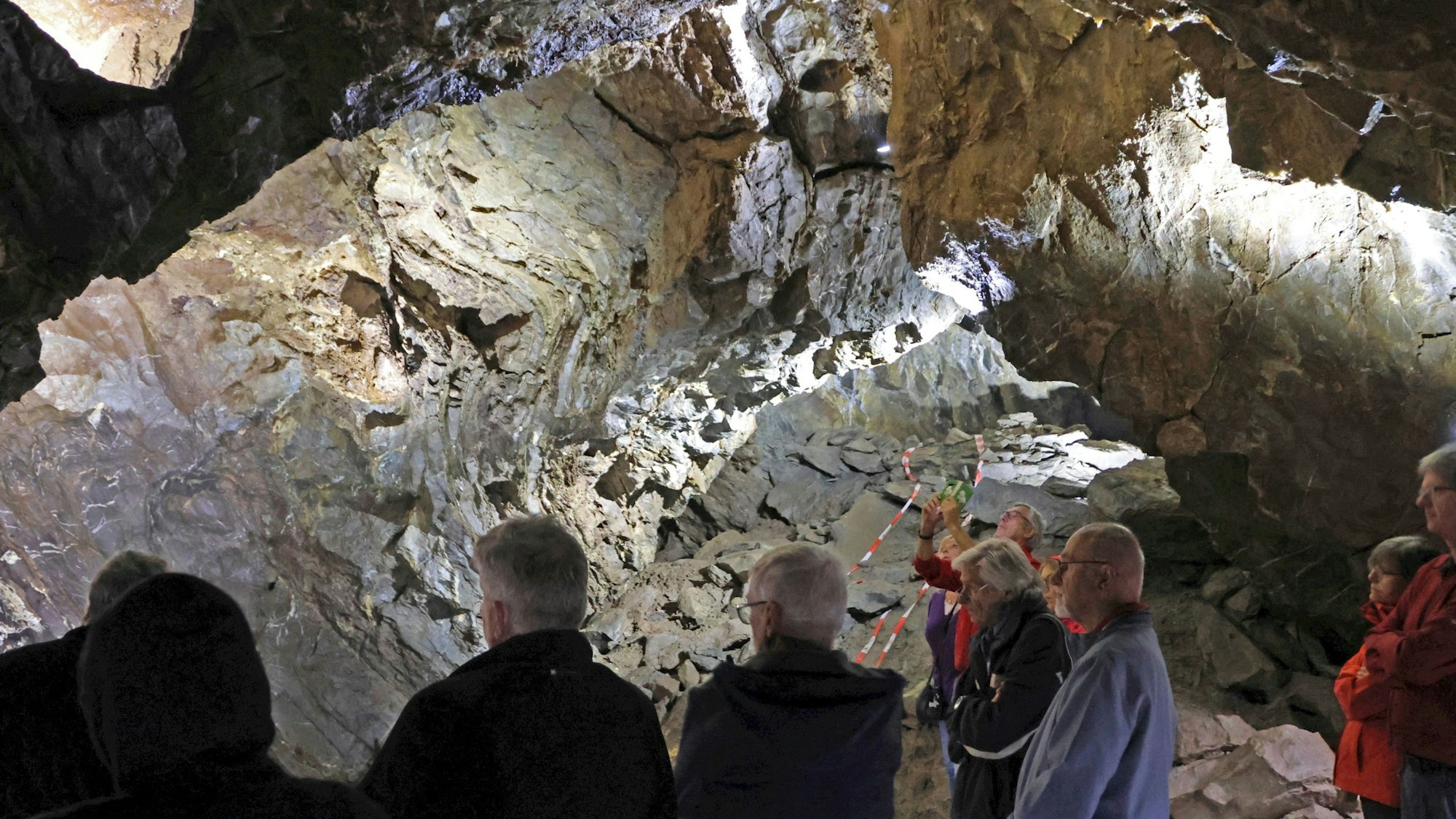 Eine Besuchergruppe betrachtet eine Höhlenwand.