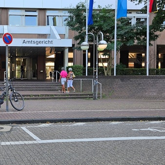 Das Foto zeigt den Eingang zum Gerichtskomplex in Köln. Ein Polizeiwagen steht davor.