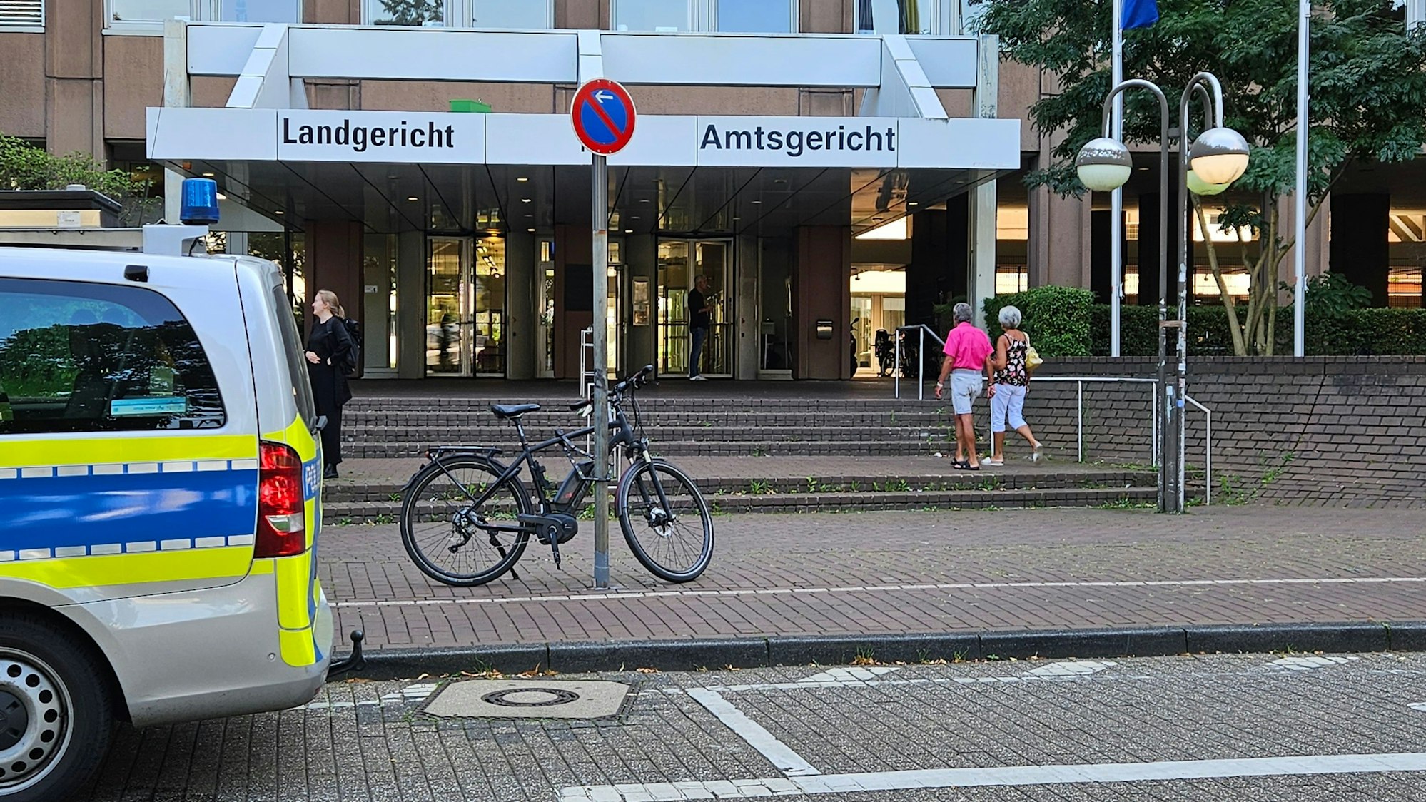 Das Foto zeigt den Eingang zum Gerichtskomplex in Köln. Ein Polizeiwagen steht davor.