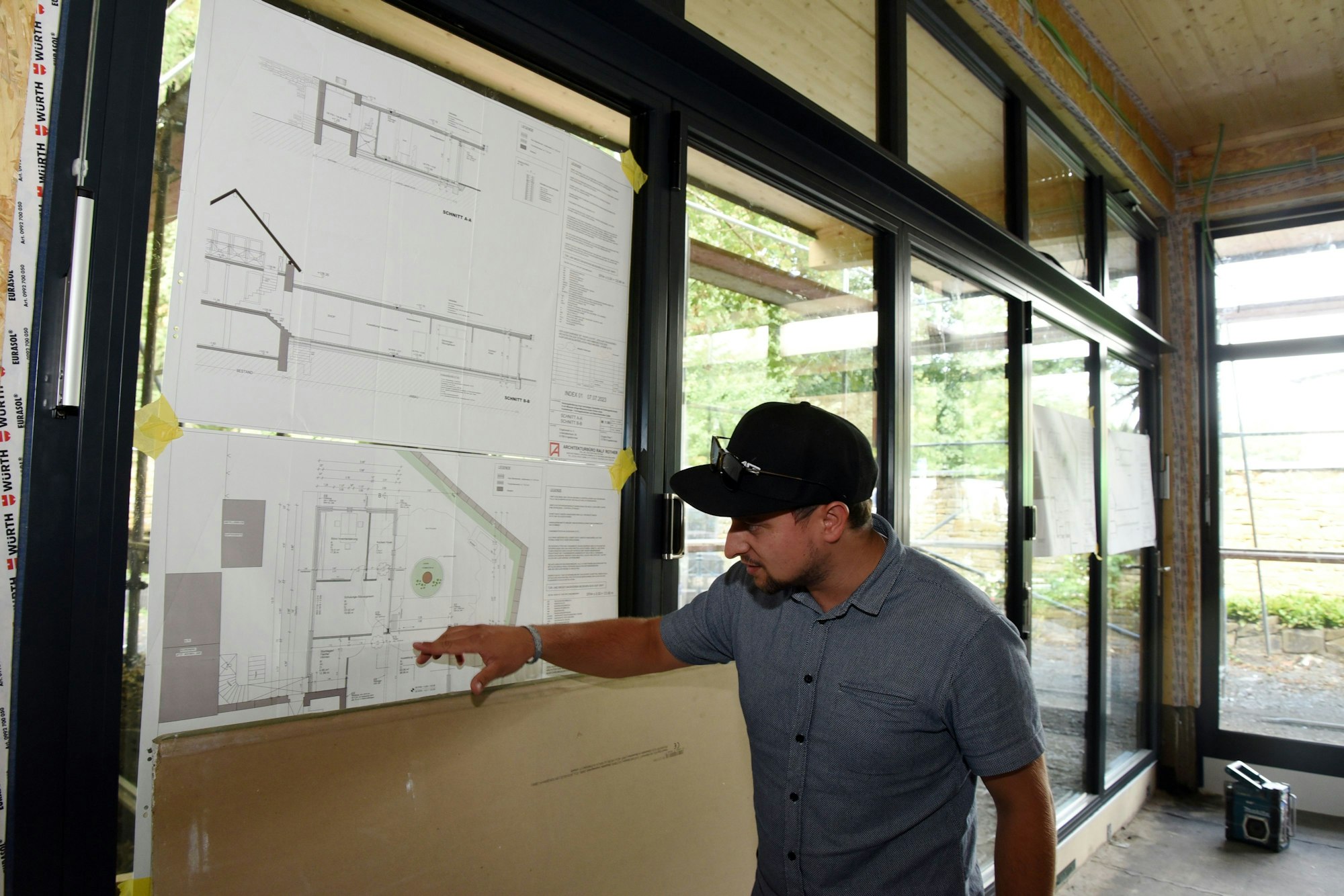 Tim Rother deutet auf einen an der Wand befestigten Bauplan im Anbau des Engel-Museums.