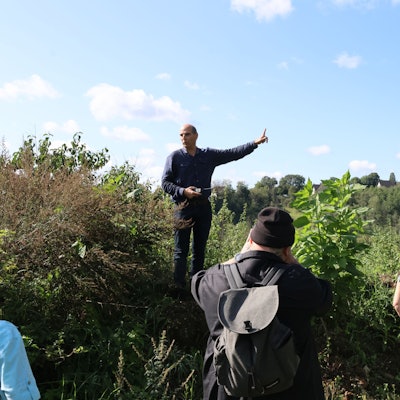 Die Gruppe der Interessierten ist auf einer Anhöhe oberhalb des Hallenbades „Monte Mare“ in Reichshof-Eckenhagen angekommen. Dort nimmt Investor Markus Lüdorf – mit dem Finger zeigend – Stellung zum geplanten Parkplatz für die Sommerrodelbahn.