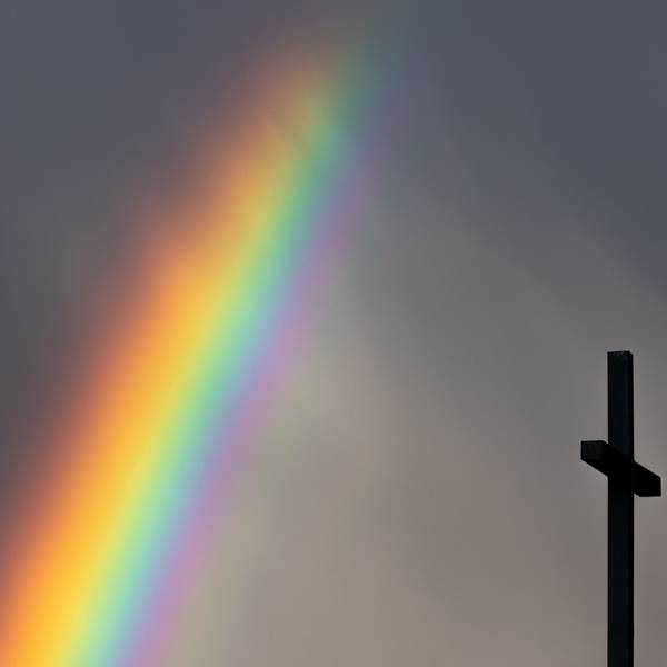 Köln: Ein kräftiger Regenbogen ist am dunklen Himmel neben dem Kreuz einer Kirche zu sehen.
