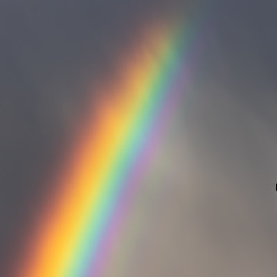 Köln: Ein kräftiger Regenbogen ist am dunklen Himmel neben dem Kreuz einer Kirche zu sehen.