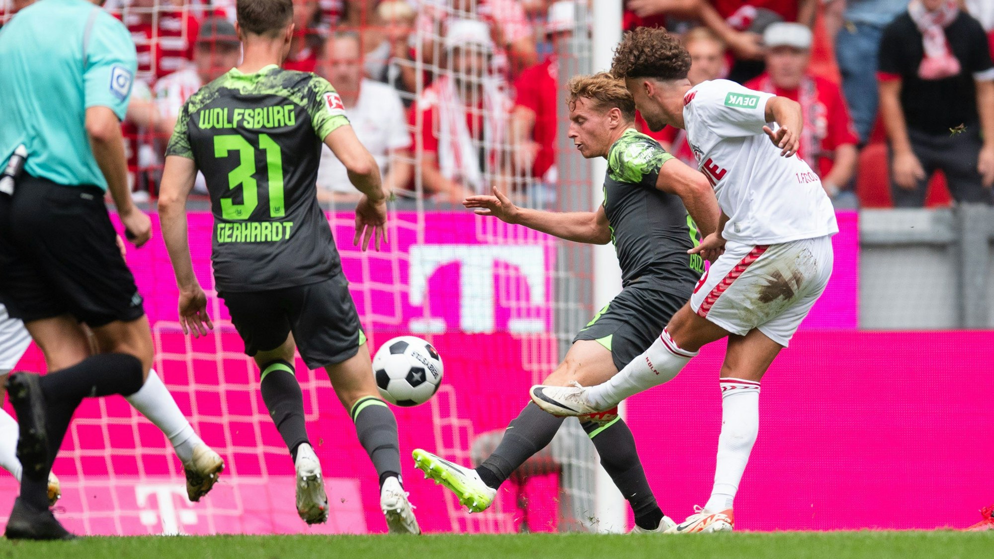26.08.2023, Nordrhein-Westfalen, Köln: Fußball: Bundesliga, 1. FC Köln - VfL Wolfsburg, 2. Spieltag, RheinEnergieStadion. Kölns Luca Waldschmidt (r) trifft zur 1:0 Führung. Daneben stehen Wolfsburgs Yannick Gerhardt (l) und Nicolas Cozza. Foto: Marius Becker/dpa - WICHTIGER HINWEIS: Gemäß den Vorgaben der DFL Deutsche Fußball Liga bzw. des DFB Deutscher Fußball-Bund ist es untersagt, in dem Stadion und/oder vom Spiel angefertigte Fotoaufnahmen in Form von Sequenzbildern und/oder videoähnlichen Fotostrecken zu verwerten bzw. verwerten zu lassen. +++ dpa-Bildfunk +++