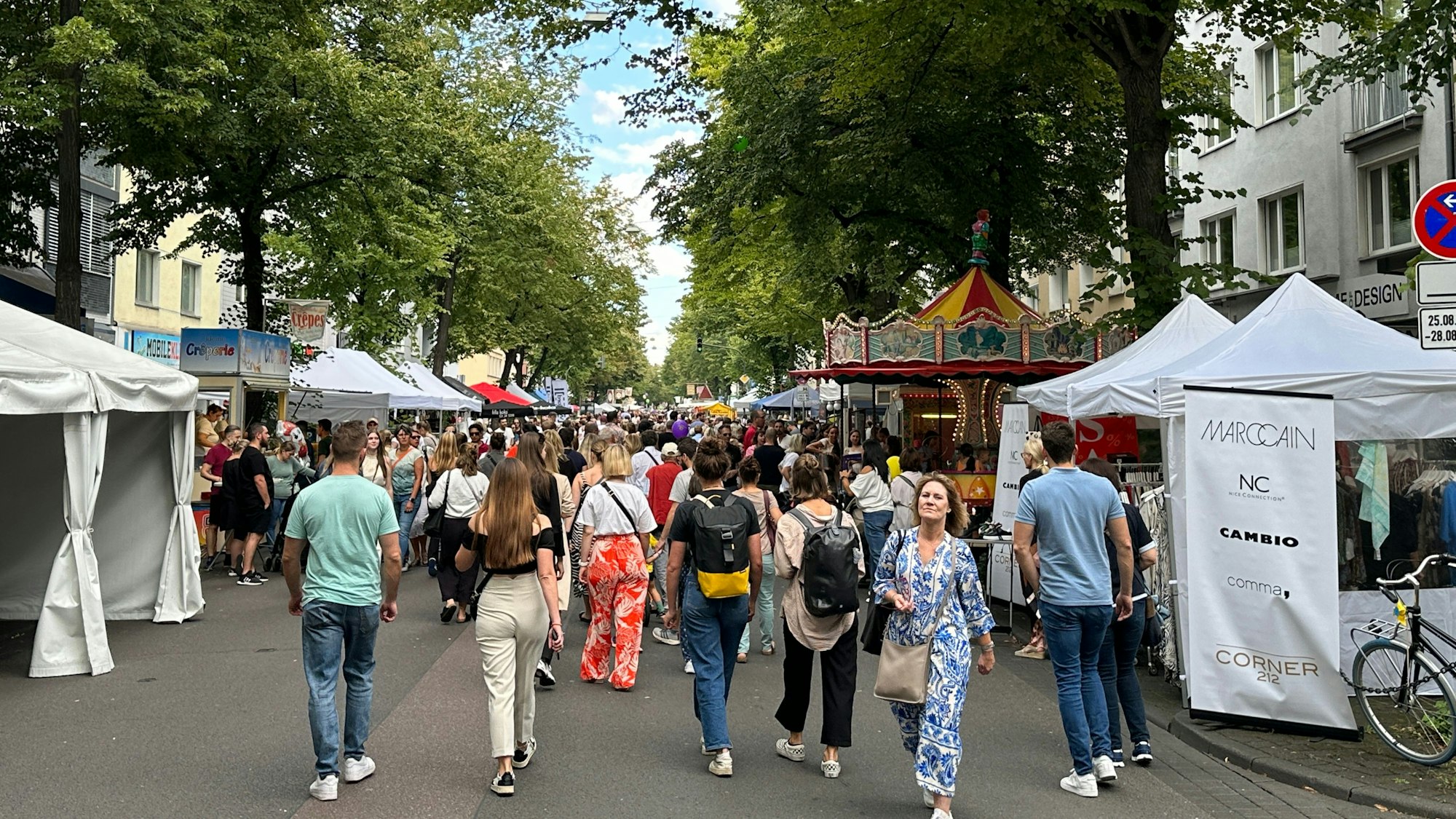 Menschen flanieren zwischen Ständen.