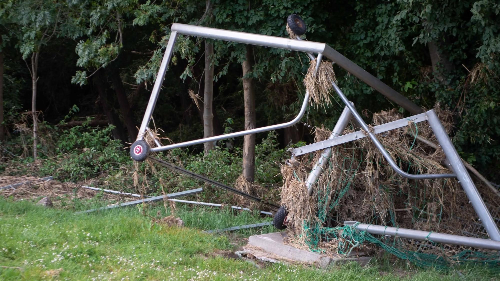 Das Bild zeigt zwei Fußballtore, die durch die Wassermassen umgekippt worden sind. In ihnen hat sich Stroh verfangen.