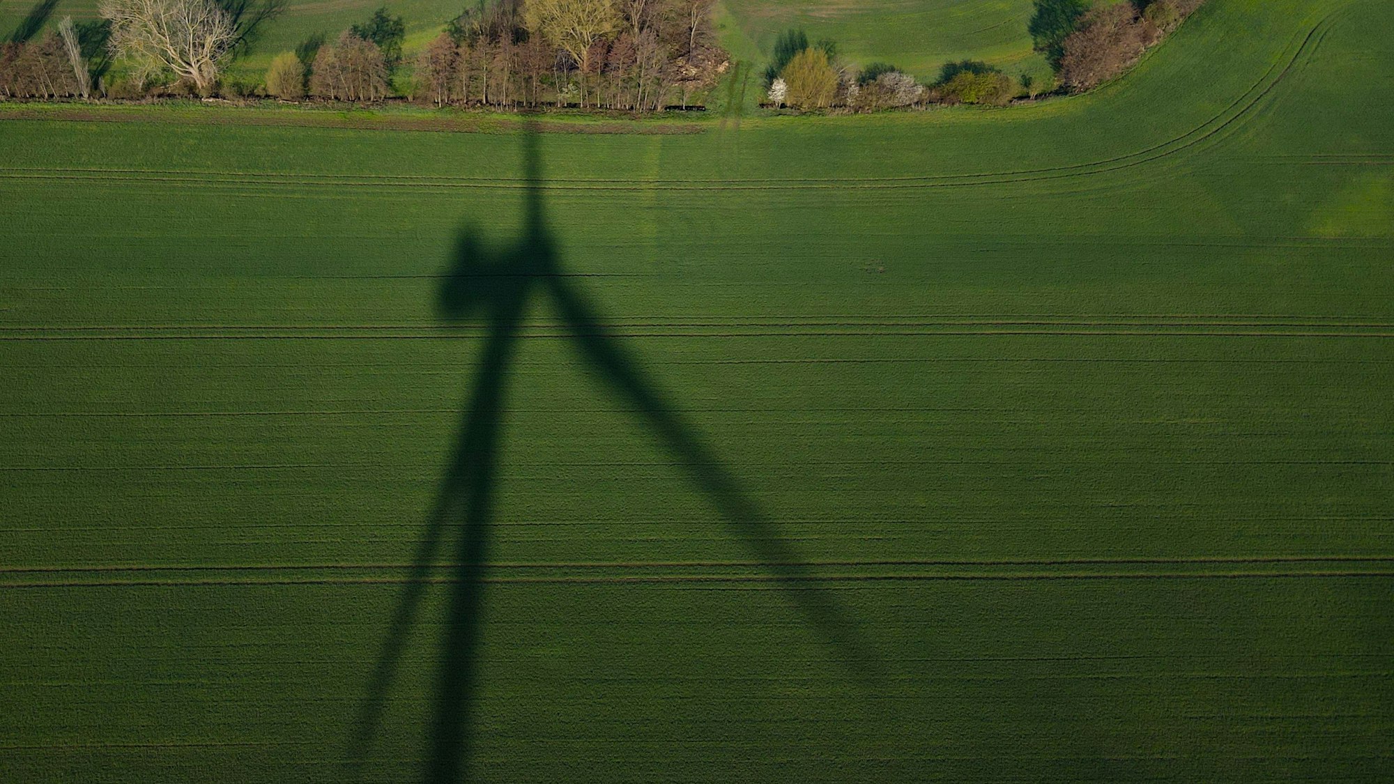 Der Schatten einer Windenergieanlage ist auf einem Feld im Landkreis Oder-Spree zu sehen (Luftaufnahme mit einer Drohne).