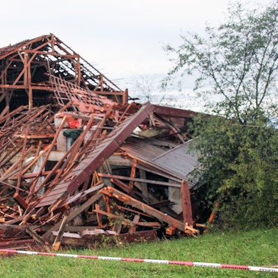 Holzbalken und Dachteile eines teilweise eingestürztes Hauses liegen nach einem heftigen Unwetter auf einem Grundstück.